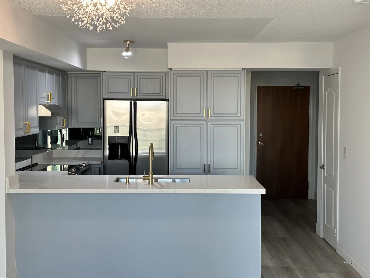 Refinished grey kitchen cabinets with gold hardware and quartz countertop