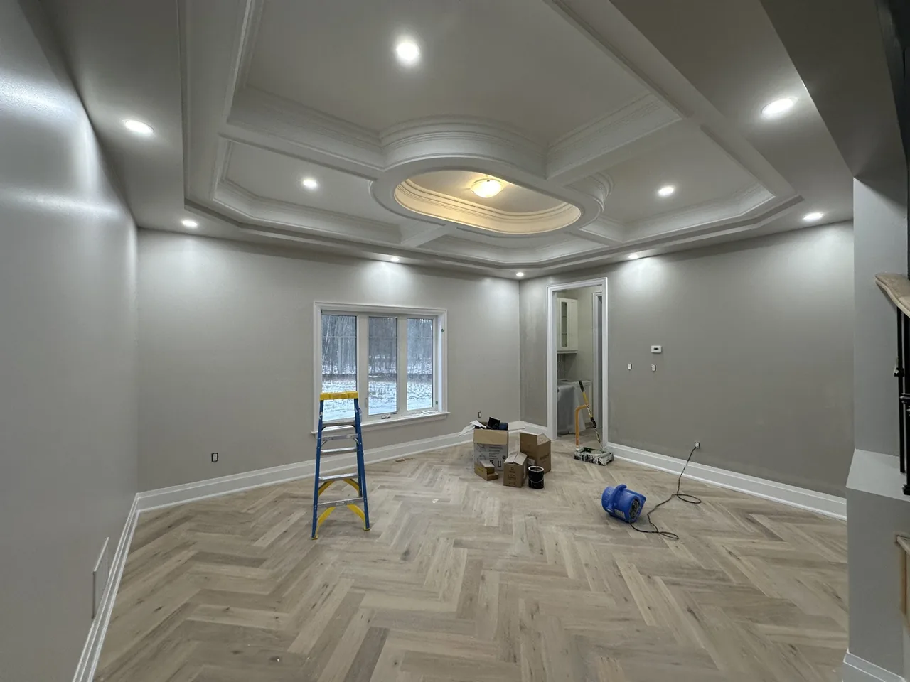 Custom home great room with a painted coffered ceiling and herringbone floor