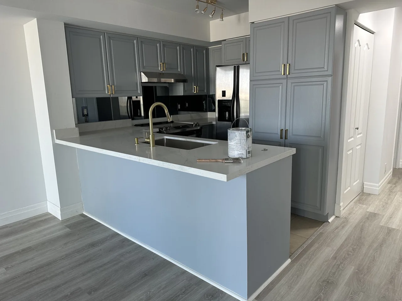 Refinished kitchen with grey cabinets, gold faucet and quartz counter