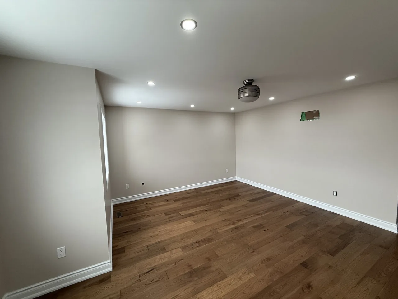 Freshly painted room with dark hardwood flooring and crisp white trim